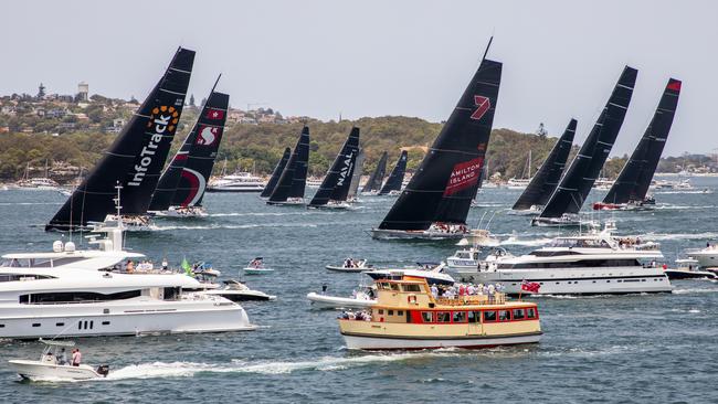 Competitors, back, race past spectators at the start of the 75th Sydney Hobart yacht race. Picture: AP