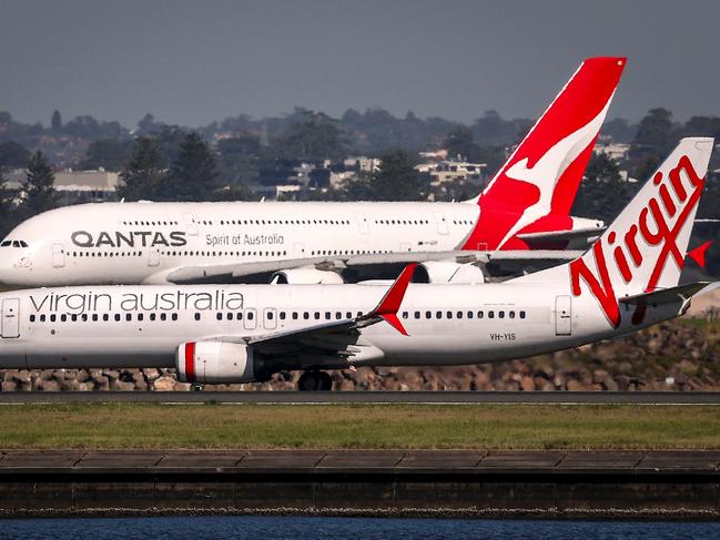 A Qantas Airways Airbus A380 plane sits on the runway as a Virgin Australia Airlines Boeing 737-800 plane prepares to take off at Sydney International Airport on April 3, 2025. (Photo by DAVID GRAY / AFP)