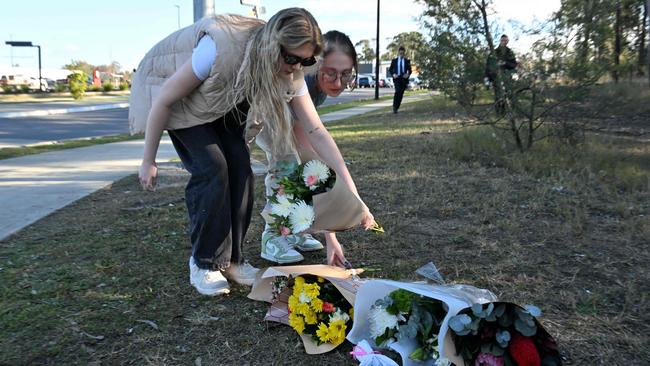 Two women lay flowers on the side the road some 500 metres from the crash site. Picture: AFP