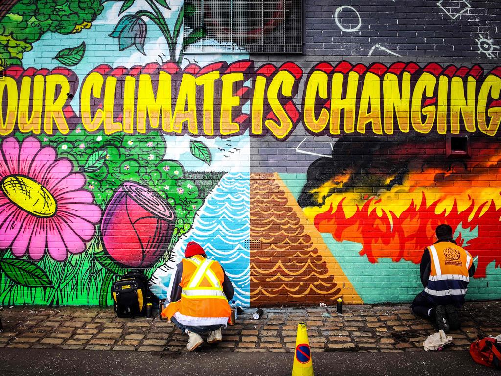 Street artists paint a mural on a wall opposite the COP26 climate summit venue in Glasgow. Picture: AFP