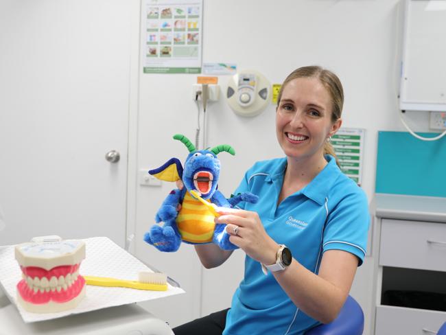 Cairns and Hinterland Health and Hospital Service oral health team leader Stephanie Wallace demonstrates how to brush teeth on a dragon prop, to help children understand the importance of oral hygiene. Photo: Catherine Duffy.