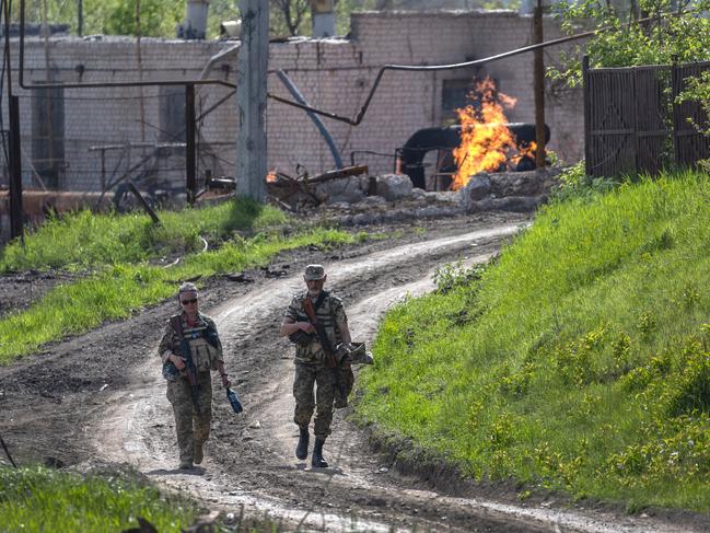Ukrainian Army soldiers walk past a burning natural gas terminal on the northern outskirts of Kharkiv, Ukraine. Picture: John Moore/Getty Images
