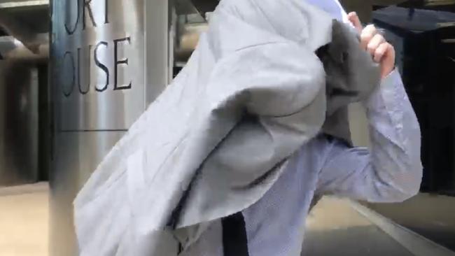 Joshua Peter Gearon covers his face as he leaves court. Picture: 7 NEWS Gold Coast