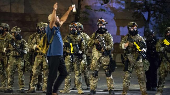 A protester holds his hands in the air while walking past a group of federal officers during a demonstration in Portland. Picture: Getty