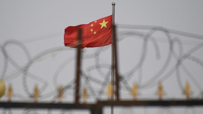 The Chinese flag behind razor wire at a housing compound in Yangisar, south of Kashgar, in China's western Xinjiang region. Picture: AFP