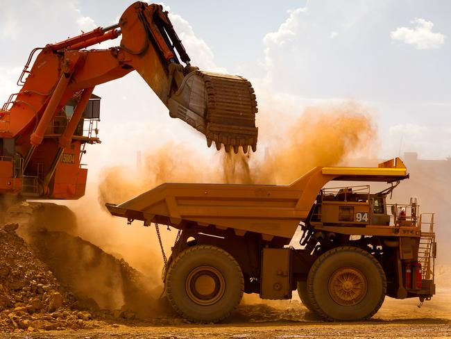 A haul truck is loaded by a digger with material from the pit at Rio Tinto Group's West Angelas iron ore mine in Pilbara, Australia, on Sunday, Feb. 19, 2012. Rio Tinto Group, the world's second-biggest iron ore exporter, will spend $518 million on the first driverless long-distance trains to haul the commodity from its Western Australia mines to ports, boosting efficiency. Photographer: Ian Waldie/Bloomberg via Getty Images