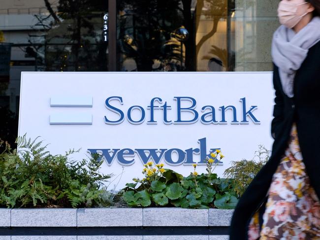 A pedestrian walks past signage outside the building where the SoftBank Group headquarters is located in Tokyo on February 8, 2022. (Photo by Kazuhiro NOGI / AFP)