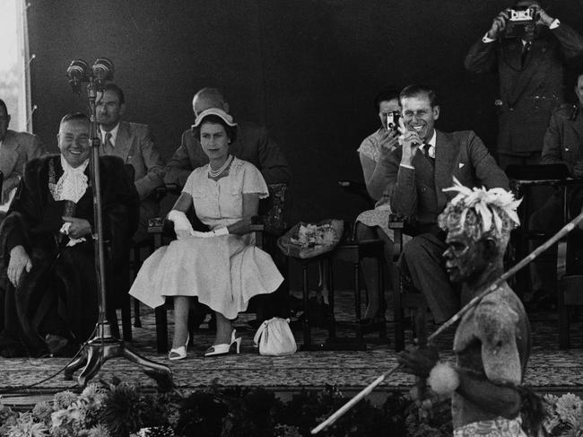 Queen Elizabeth II and Prince Philip (laughing) watch an aboriginal display and wallaby dance at the Exhibition Grounds in Brisbane, during the royal tour of Australia in March 1954. Picture: Paul Popper/Popperfoto/Getty Images