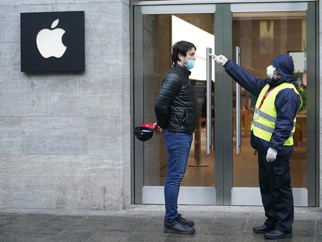 A security guard checks the body temperature of a customer waiting to enter the Berlin Apple store on the first day the store reopened since March. Picture: Getty Images