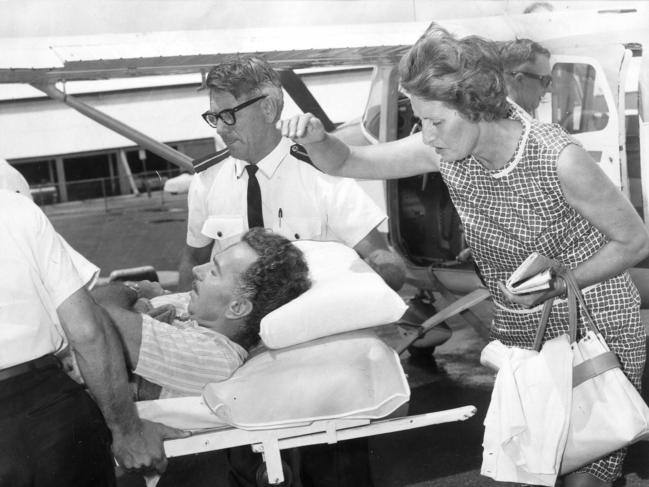 Ron and Joyce Linfoot being helped by paramedics after being ambushed by two criminals alongside a lonely stretch of Queensland. Picture: 1967