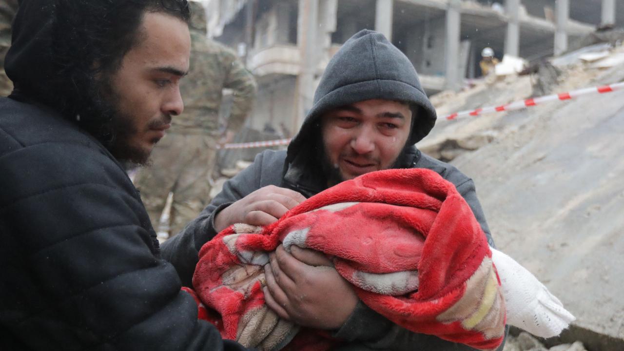 A Syrian man weeps as he carries the body of his son who was killed in the earthquake (Photo by Bakr ALKASEM / AFP)