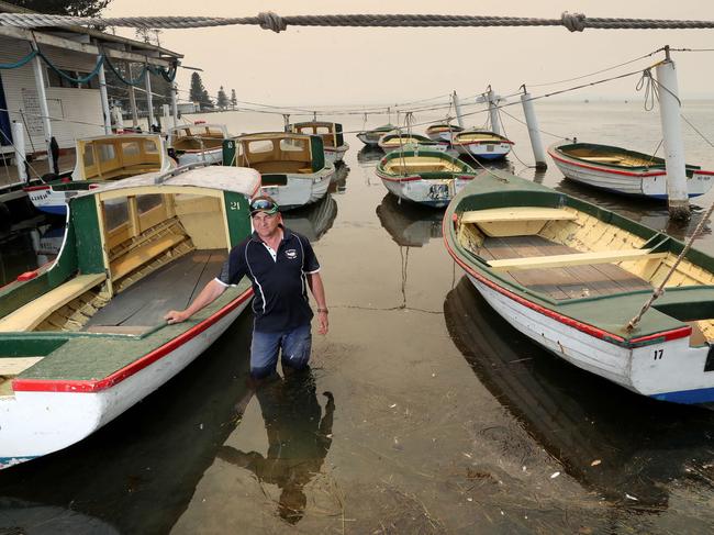 Mr Moon stands in the shallows with his boat fleet. Picture: Sue Graham