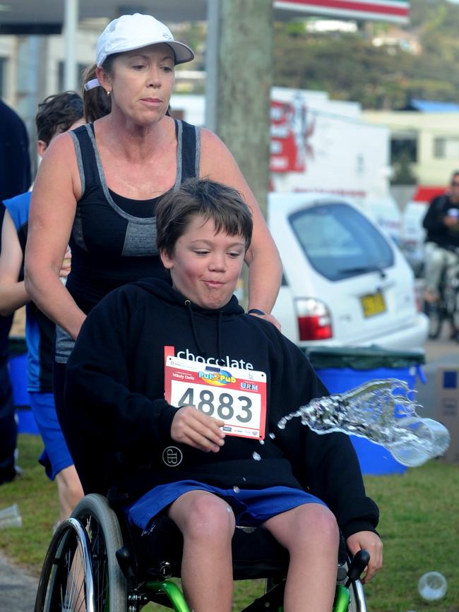 A wheelchair competitor cools off at the water station on Ocean St, Narrabeen, in 2011. Picture: Simon Cocksedge