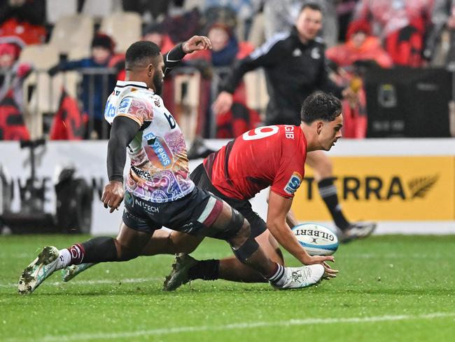 Crusaders' Noah Hotham dives for a try under pressure from Reds’ Filipo Daugunu. Picture: AFP