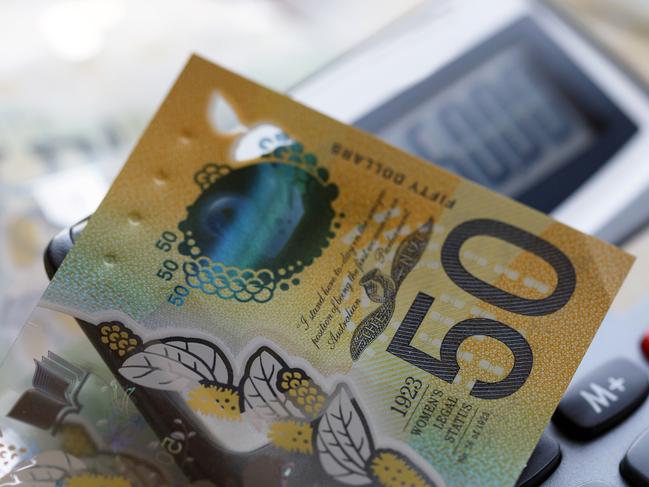 Australian fifty dollar bill over a calculator. The new issue is designed to deter counterfeiting, the note is polymer and water resistant with a clear holographic strip; money generic