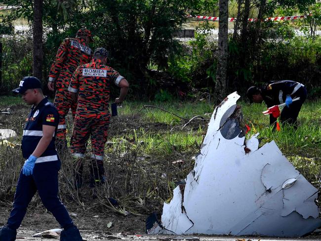 Members of the fire and rescue department inspect the crash site of a plane in Shah Alam, Malaysia's Selangor state on August 17, 2023. A light plane crashed on a street in Malaysia's central Selangor state on Thursday, killing eight people on board and two motorists on the ground, authorities said. (Photo by Muhammad Lutfi / AFP)