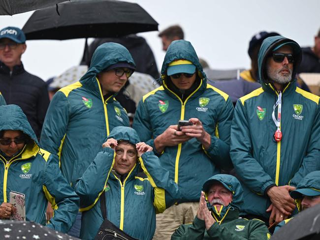 Australia fans shelter from the rain on day three of the fourth Ashes cricket Test match between England and Australia at Old Trafford cricket ground in Manchester, north-west England on July 21, 2023. (Photo by Oli SCARFF / AFP) / RESTRICTED TO EDITORIAL USE. NO ASSOCIATION WITH DIRECT COMPETITOR OF SPONSOR, PARTNER, OR SUPPLIER OF THE ECB