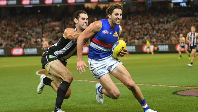 Brodie Grundy of the Magpies (left) runs down Bulldogs’ midfielder Marcus Bontempelli. Picture: AAP Image/Julian Smith