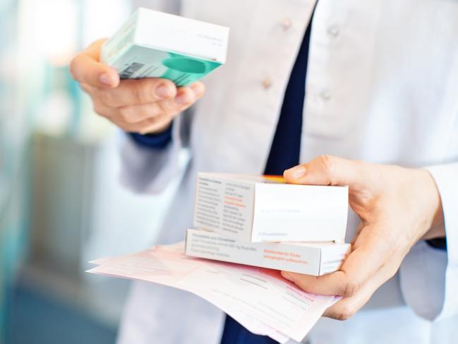 Closeup of pharmacist's hands taking medicines from shelf at the pharmacy