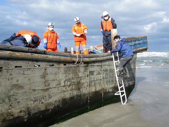 CORRECTION - This handout picture taken on November 27, 2017 by the Oga city municipal office and released via Jiji Press shows coast guard officers inspecting a battered wooden boat where eight bodies were found inside at a beach in Oga, Japan's Akita prefecture. Japanese coastguard officials spotted eight bodies inside a battered wooden boat off northern Akita prefecture but waves had prevented officials from investigating since the boat was first spotted on November 24. Dozens of North Korean fishing vessels wash up on Japan's coast every year. Sometimes the boats' occupants have already died at sea, a phenomenon local media refer to as "ghost ships".   / AFP PHOTO / JIJI PRESS / Handout /  - Japan OUT / RESTRICTED TO EDITORIAL USE - MANDATORY CREDIT "AFP PHOTO / OGA CITY MUNICIPAL OFFICE / JIJI PRESS" - NO MARKETING NO ADVERTISING CAMPAIGNS - DISTRIBUTED AS A SERVICE TO CLIENTS / “The erroneous mention[s] appearing in the metadata of this photo by Handout has been modified in AFP systems in the following manner: [adds JAPAN OUT in geographical restriction]. Please immediately remove the erroneous mention[s] from all your online services and delete it (them) from your servers. If you have been authorized by AFP to distribute it (them) to third parties, please ensure that the same actions are carried out by them. Failure to promptly comply with these instructions will entail liability on your part for any continued or post notification usage. Therefore we thank you very much for all your attention and prompt action. We are sorry for the inconvenience this notification may cause and remain at your disposal for any further information you may require.”