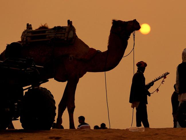 A man walks with his camel during sunset on New Year's Eve in Karachi, Pakistan on December 31, 2023. Picture: AFP