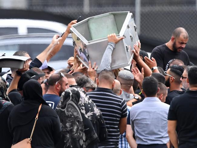 Mourners lift an empty coffin above their heads after he was buried. Picture: AAP