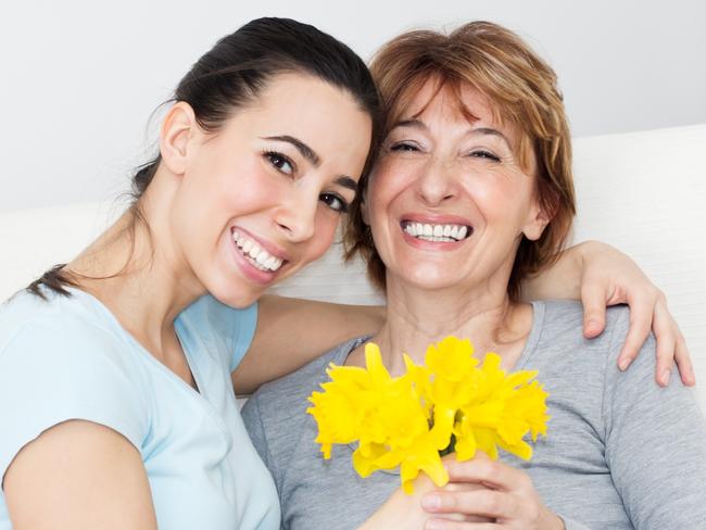 Beautiful young woman giving to her mother flowers for Mother's Day.