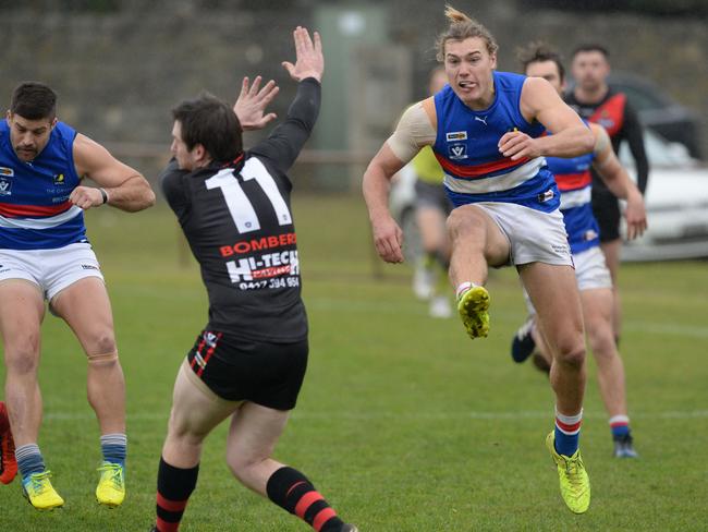 Mornington’s Tom Hobbs boots the ball past Frankston’s Waide Symes. Picture: AAP/Chris Eastman