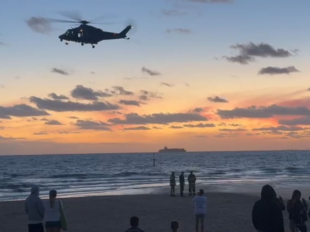 A helicopter circles St Kilda Beach after a body was seen submerged in the water.