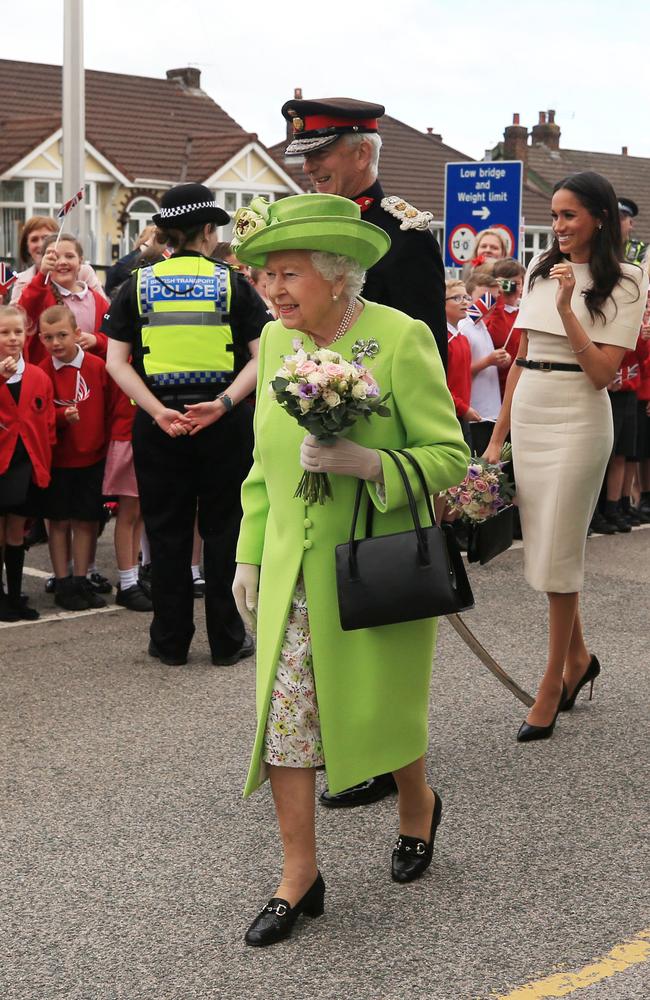 Queen Elizabeth II holds flowers as she shows Meghan, Duchess of Sussex, how she greets the crowds after arriving by Royal Train at Runcorn Station. Picture: Getty