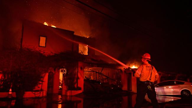 A firefighter works to put out a blaze as homes burn along Pacific Coast Highway during the Palisades Fire in Malibu on January 8. Picture: AFP