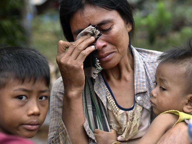 A woman carries a child in the flood ravaged village in Sanamxai, Attapeu province, in Laos. Picture: AFP