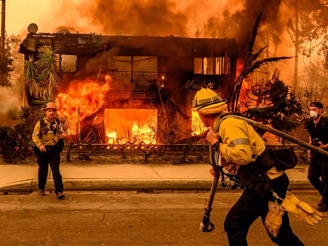 TOPSHOT - Firefighters work the scene as an apartment building burns during the Eaton fire in the Altadena area of Los Angeles county, California on January 8, 2025. At least five people are now known to have died in wildfires raging around Los Angeles, with more deaths feared, law enforcement said January 8, as terrifying blazes leveled whole streets, torching cars and houses in minutes. More than 1,000 buildings have burned in multiple wildfires that have erupted around America's second biggest city, forcing tens of thousands of people from their homes. (Photo by JOSH EDELSON / AFP)