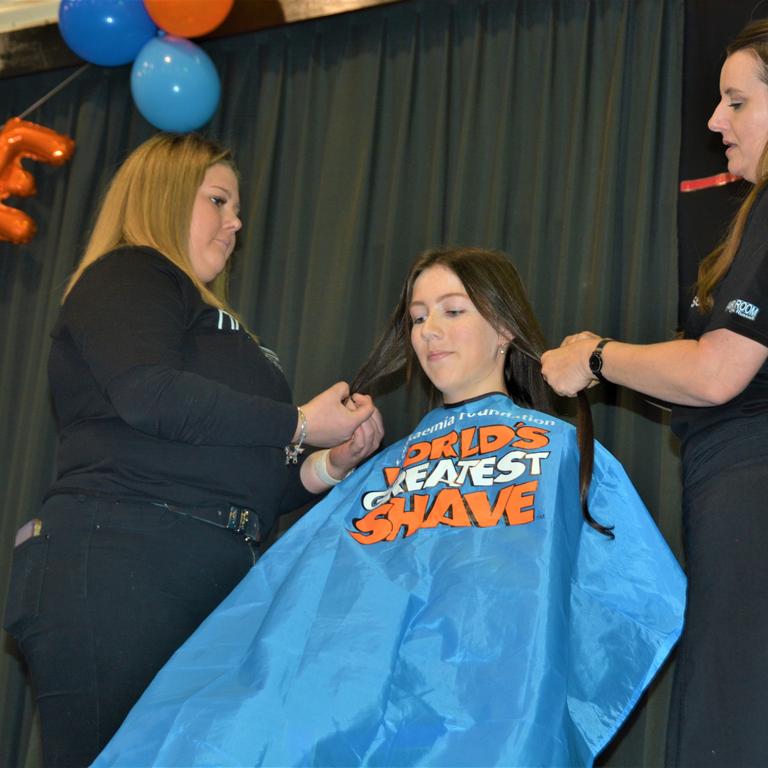 At the St Joseph's College 2023 World's Greatest Shave event is student Jessica Toohey getting her hair cut by hairdressers (from left) Georgie Harwood and Jillian Grundy from the Hair Room on Russell. Picture: Rhylea Millar