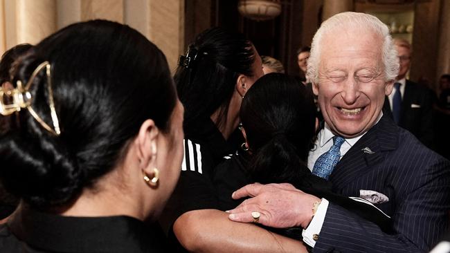 Britain's King Charles III reacts as he is hugged by members of New Zealand's Black Ferns rugby union team, at Buckingham Palace in central London on September 11, 2024. (Photo by Aaron Chown / POOL / AFP)