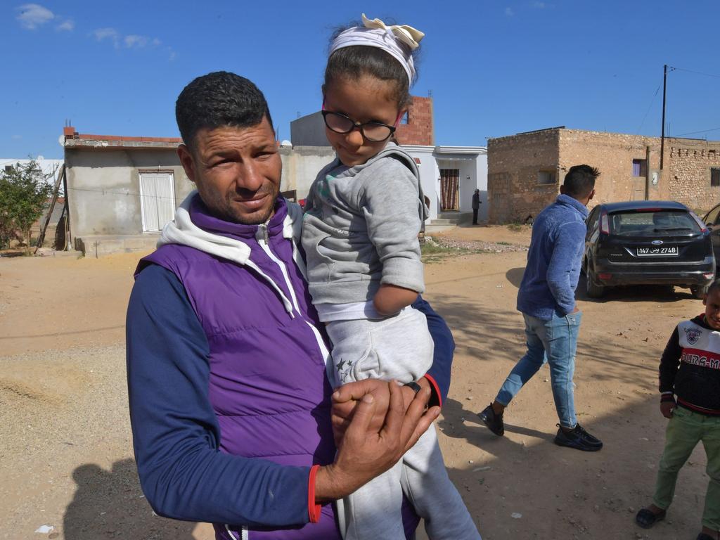 Yassin carries his daughter, the knifeman’s niece, in front of the family home in the Tunisian city of Sfax. Picture: Fethi Belaid/AFP.