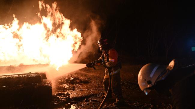 Ukrainian emergency personnel douse water to extinguish flames as they work at the site of the drone attack in Kharkiv, early on Saturday. Picture: Sergey Bobok/AFP