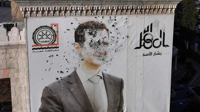 A bullet-riddled portrait of Syrian President Bashar al-Assad adorning Hama's municipality building after it was defaced following the capture of the city. Picture: AFP