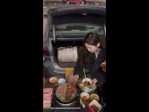 Woman cooks meal for friends out of car boot