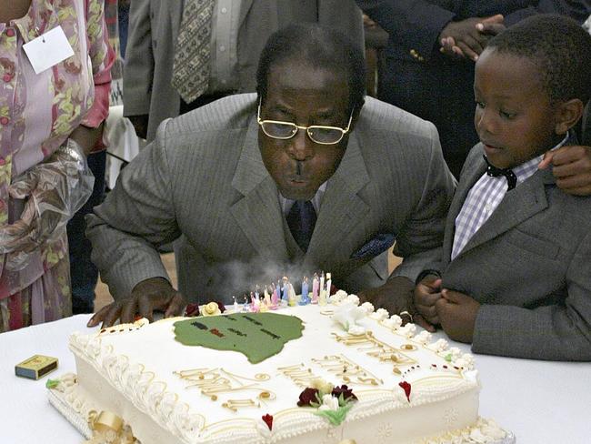 Birthday cake ... Zimbabwe President Robert Mugabe blows the candles out on his 80th birthday cake with his youngest son Chatunga in Kutama in 2004. Picture: AP