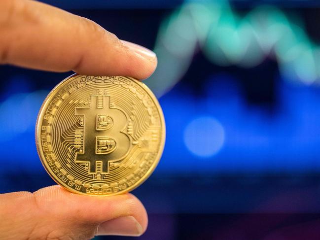 A picture taken on February 6, 2018 shows a person holding a visual representation of the digital crypto-currency Bitcoin, at the "Bitcoin Change" shop in the Israeli city of Tel Aviv. / AFP PHOTO / JACK GUEZ