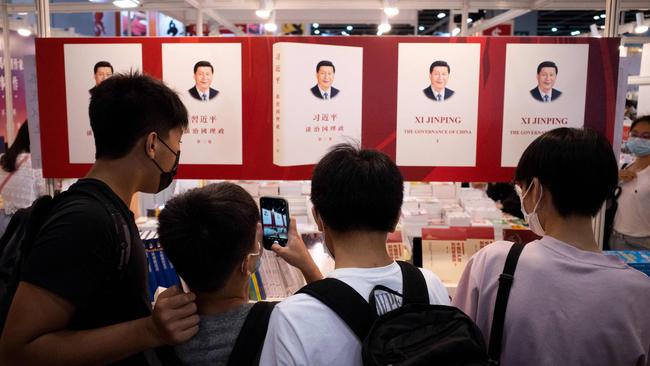 Teenagers take photos of a banner illustrating a book by Chinese President Xi Jinping at the annual Hong Kong Book Fair. Picture: AFP