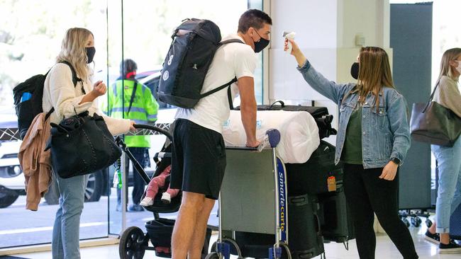 AFL players, their wives, girlfriends and families on their way to Queensland. Carlton’s Matthew Kreuzer gets his temperature checked by Nadine Rabah from the AFL. Picture: Mark Stewart