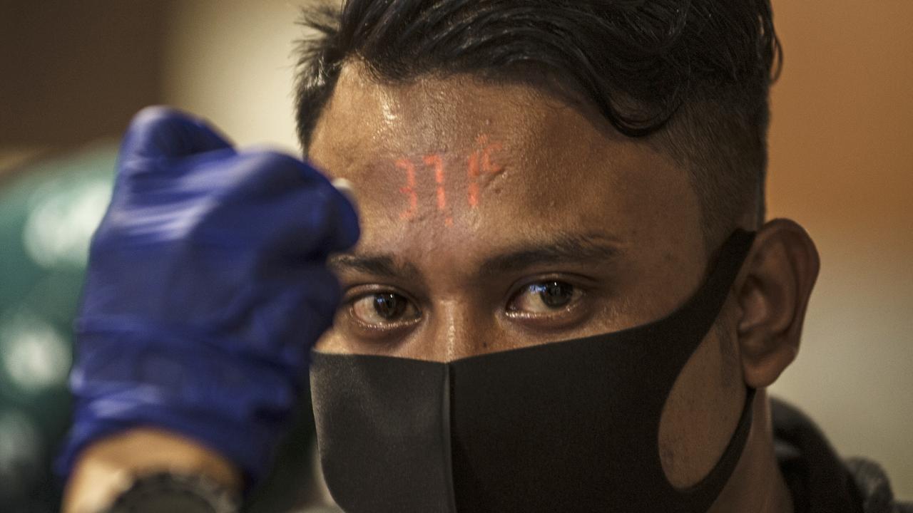 A traveller has his temperature checked upon arrival from Kuala Lumpur. Picture: AP Photo/Kusumadireza)