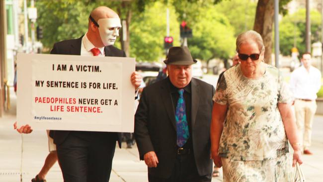  Vivian Frederick Deboo, centre, and his wife Margaret, right, are confronted by one of his victims "B", as he enters the District Court to face sentencing submissions in November.