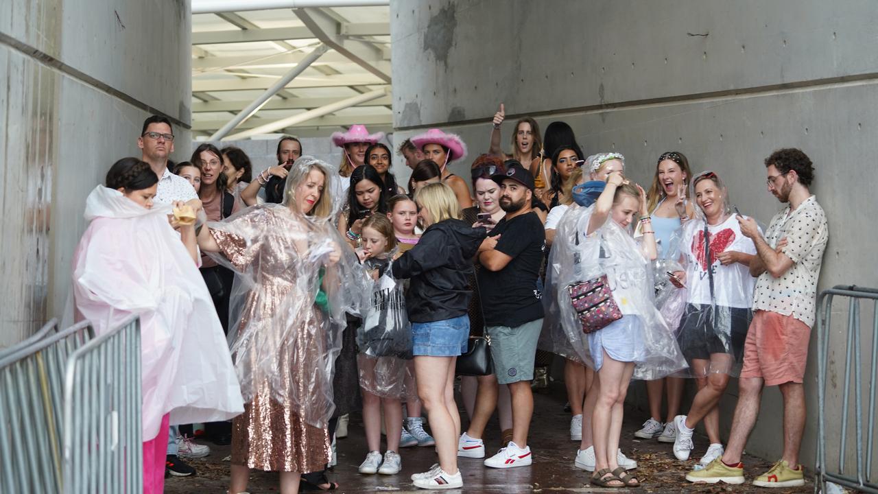 Taylor Swift fans duck for cover as a thunderstorm spreads over Sydney just hours before the pop star takes the stage. Photo: Tom Parrish