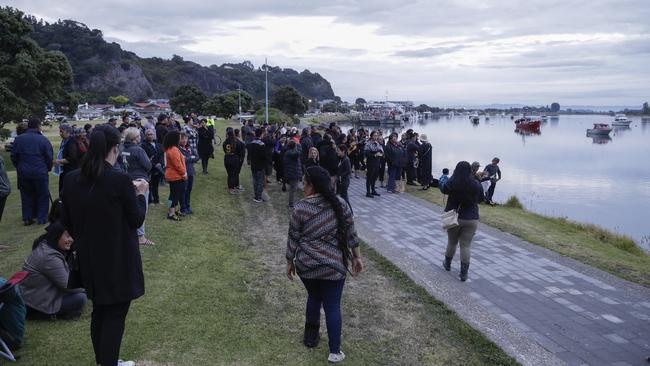 Locals sing during sun rise as they wait for the return of the victims after the White Island eruption to be returned to Whakatane. Picture: AP