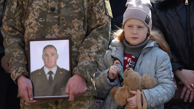 Daughter of Rostyslav Romanchuk stands near the portrait of her father his funeral. Picture: AFP