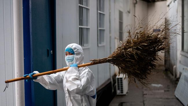 A worker wearing a hazmat suit carries a broom in Huanggang Zhongxin Hospital in Huanggang. Picture: AFP.