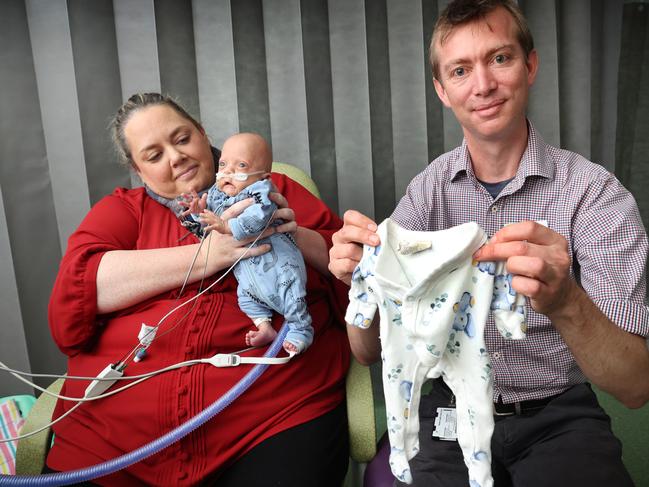 Ms Phillips and baby Oskar, with neonatologist Damien Gilby holding the smallest jumpsuit for a baby that Oskar has finally outgrown. Picture: David Caird